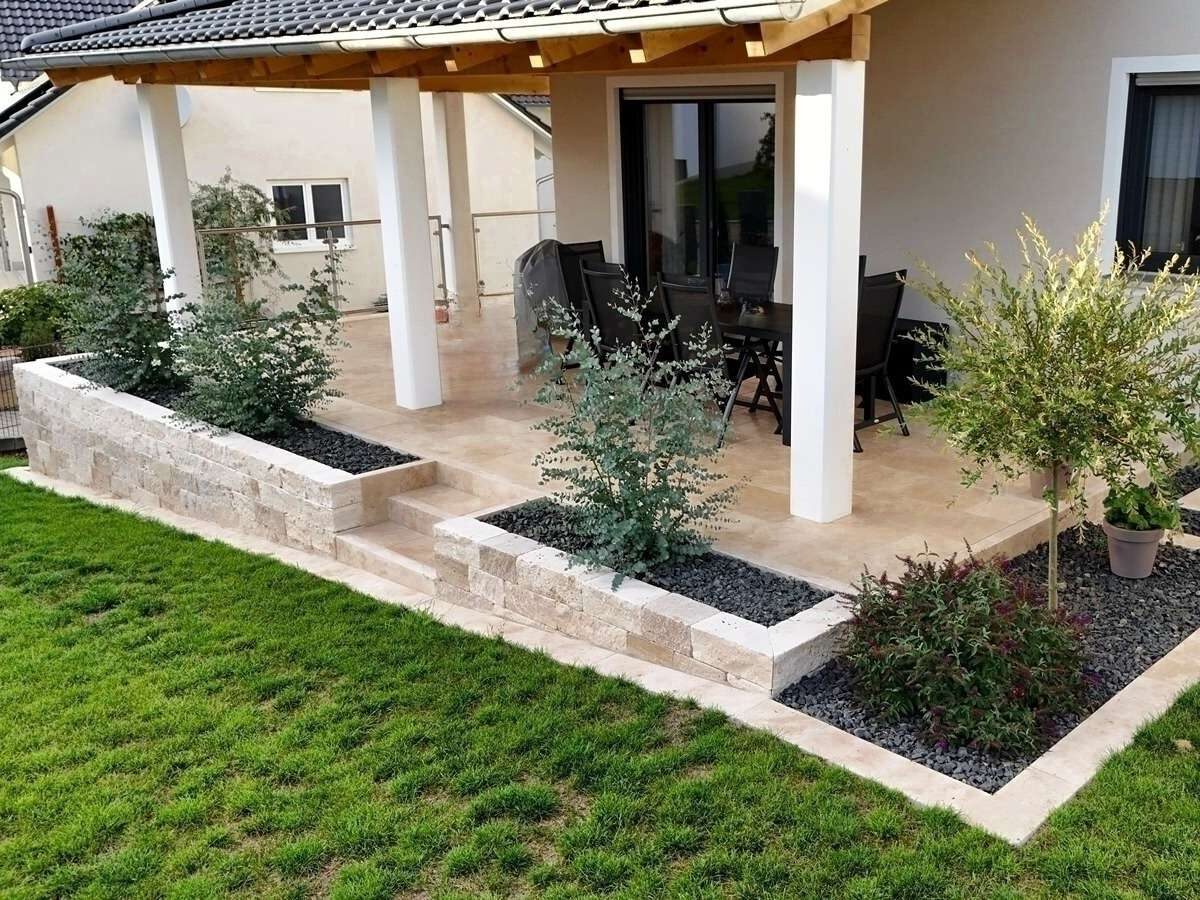 Erhöhte Terrasse mit Natursteinmauer, Treppe und moderner Bepflanzung an einem Einfamilienhaus in Ingolstadt