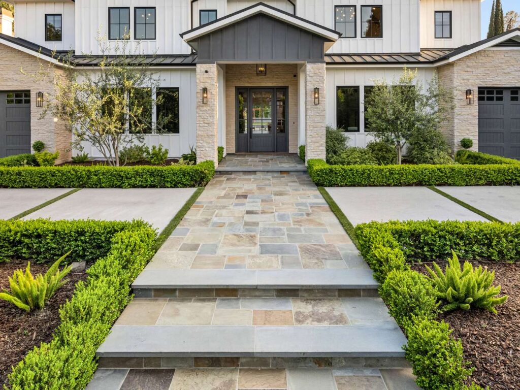 Naturstein-Hauseingang mit modernen Pflasterstufen, gepflegtem Vorgarten und symmetrischer Bepflanzung in Ingolstadt
